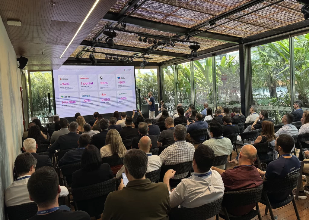 Palestra da 1ª edição do Lecom Intelligent Operations em São Paulo, com executivos assistindo à apresentação de cases de sucesso em uma grande tela.